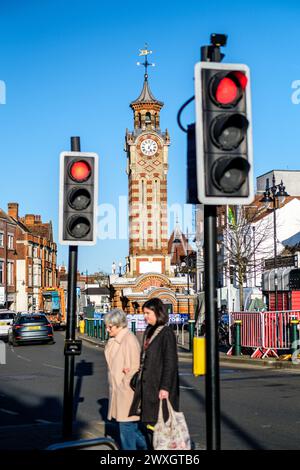 Epsom Surrey, Großbritannien, März 30 2024, Red oder Stop Ampel with Two Women Crossing Road Tragen Einkaufstaschen Stockfoto