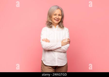 Porträt einer grauhaarigen Reifen Frau, die mit gefalteten Armen posiert Stockfoto