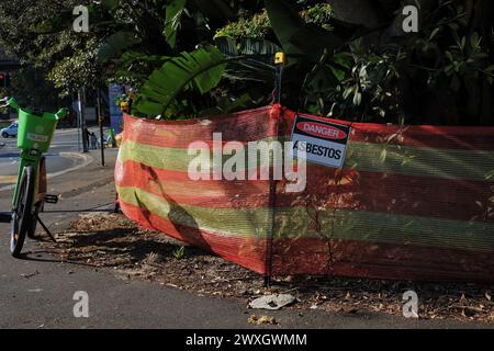 Gelbes und orangefarbenes Barrierezeichen und Gefahrenasbestschild entlang des St Marys Rd Fußweges wegen asbestkontaminiertem Mulch im Cook + Phillip Park, Sydney Stockfoto