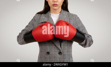 Entschlossene Geschäftsfrau mit Boxhandschuhen im Business-Anzug Stockfoto