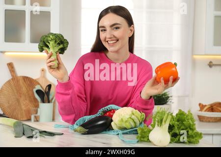 Frau mit Gemüse und Schnur-Tasche am hellen Marmortisch in der Küche Stockfoto