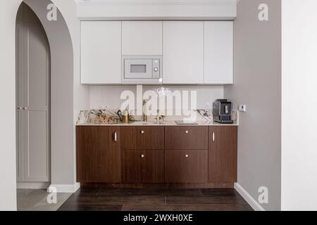 Holzschrank, Waschbecken, Mikrowelle und Kaffeemaschine in der Küche Stockfoto