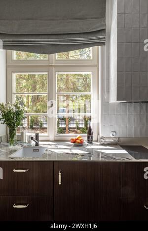 Gebäude mit Schränken, Arbeitsplatte, Waschbecken, Herd, Fenster, und Holzarmaturen Stockfoto