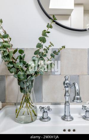 Weiße Vase mit Landpflanze auf Tisch neben Spiegel im Innendesign Stockfoto