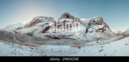 Ein Panoramablick auf die drei Schwestern Berge in Glencoe, bedeckt mit Schnee an einem sonnigen Tag. Schottische Highlands. Stockfoto