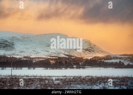 Eine schneebedeckte Berglandschaft bei Sonnenuntergang in Laggan, Schottland Stockfoto
