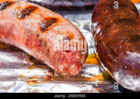 Zwei Hotdogs auf Folie, einer mit geschmolzenem Käse Stockfoto