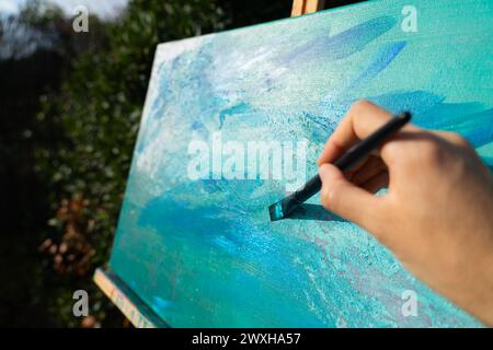 Pinsel eine Leinwand mit blauer Acrylfarbe Stockfoto