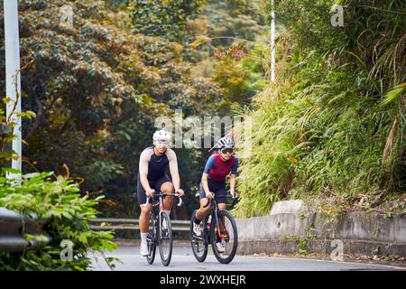 Junge asiatische Radfahrer, die auf der Landstraße Fahrrad fahren Stockfoto