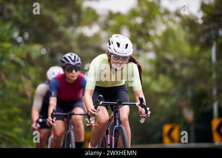 Gruppe von drei jungen asiatischen erwachsenen Radfahrern, die Fahrrad auf der Landstraße fahren Stockfoto