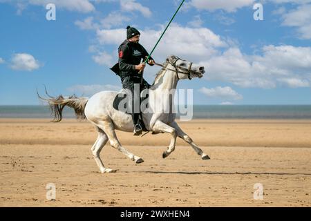 Altes Kavallerie-Spiel „Zelt-Pegging“ Reiter in Southport, Merseyside, 31.03.2024. Eine Gruppe von Männern spielt ihren Lieblingssport am Strand von Southport in der wunderschönen Ostersonne. Das Spiel, in Pakistan auch als Neza Bazi bekannt, ist eine Reitersportart uralten Ursprungs und ist eine von nur zehn von der International Equestrian Federation offiziell anerkannten Reitdisziplinen. Quelle: Cernan Elias/Alamy Live News Stockfoto