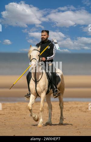 Altes Kavallerie-Spiel „Zelt-Pegging“ Reiter in Southport, Merseyside, 31.03.2024. Eine Gruppe von Männern spielt ihren Lieblingssport am Strand von Southport in der wunderschönen Ostersonne. Das Spiel, in Pakistan auch als Neza Bazi bekannt, ist eine Reitersportart uralten Ursprungs und ist eine von nur zehn von der International Equestrian Federation offiziell anerkannten Reitdisziplinen. Quelle: Cernan Elias/Alamy Live News Stockfoto