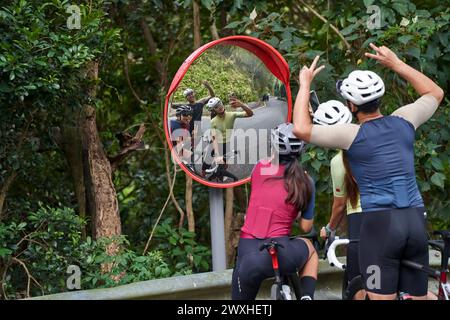 Gruppe von drei jungen asiatischen Radfahrern, die ein lustiges Selfie im Freien auf der Landstraße machen Stockfoto