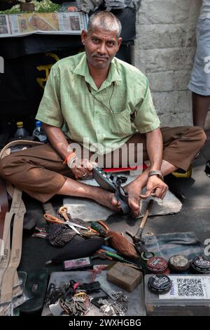 Indischer Mann repariert Schuhe auf der Straße, auch Schuhmacher, Schuster oder Mochi genannt. Schuhmacher arbeitet an einem Paar Schuhen in den Straßen von Mumbai India-Ma Stockfoto