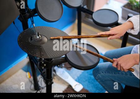 Nahaufnahme der Hände eines Teenager-Musikers, der Rhythmus der Musik kreiert, während er im stilvollen Retro-Studio Schlagzeug schlägt. Hände halten die Drumsticks und schlagen Stockfoto