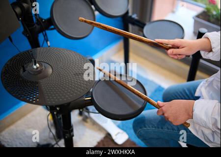 Nahansicht von oben auf die Hände des Teenager-Schlagzeugers. Teenager spielt Schlagzeug im Musikstudio. Blick von oben auf den jungen Musiker, der auf die schwarzen Zimbeln schlägt Stockfoto