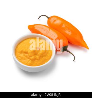 Paar frische rohe Orangen peruanische Aji Amarillo Paprika und eine Schüssel mit Aji Amarillo Sauce isoliert auf weißem Hintergrund Nahaufnahme Stockfoto