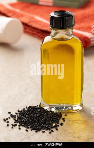 Flasche mit pflanzlichem Nigella-Öl und einem Haufen nigella-Samen aus nächster Nähe Stockfoto