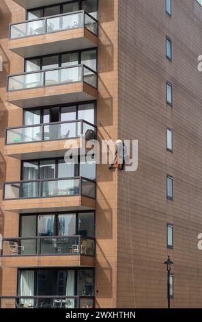 Vauxhall, London, Großbritannien. März 2024. Ein Bauunternehmer mit einem Kopf für Höhen hängt an einem Wohnblock neben der Vauxhall-Brücke und führt Wartungsarbeiten durch. Kredit: Maureen McLean/Alamy Stockfoto