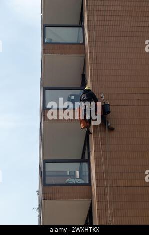 Vauxhall, London, Großbritannien. März 2024. Ein Bauunternehmer mit einem Kopf für Höhen hängt an einem Wohnblock neben der Vauxhall-Brücke und führt Wartungsarbeiten durch. Kredit: Maureen McLean/Alamy Stockfoto