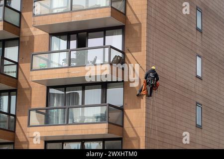 Vauxhall, London, Großbritannien. März 2024. Ein Bauunternehmer mit einem Kopf für Höhen hängt an einem Wohnblock neben der Vauxhall-Brücke und führt Wartungsarbeiten durch. Kredit: Maureen McLean/Alamy Stockfoto