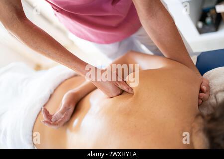 Crop-weibliche osteopathische Therapeutin, die den Rücken des Patienten massiert Stockfoto