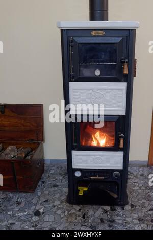 Echtes Feuer in einem Holzofen und Holzhaufen in einer Kiste in einer Wohnung in Montefiascone, Region Latium, Italien. März 31 2024 Stockfoto