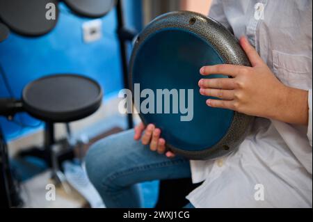 Nahaufnahme eines Jungen, der Rhythmus afrikanischer Volksmusik kreiert, spielt auf tam tam Bongo Djembe Drum in seinem Musikstudio. Genießen Sie authentische A Stockfoto