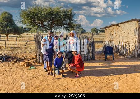 Große afrikanische Familie im Dorf vor der Außenküche, Lehmhaus im Hintergrund, gemeinnützige hilfsorganisation Stockfoto