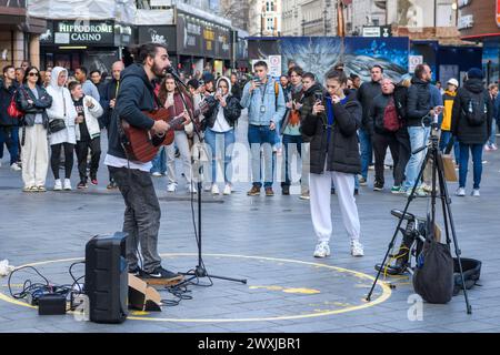 Busker spielt Gitarre und singt, Leicester Square, London Stockfoto