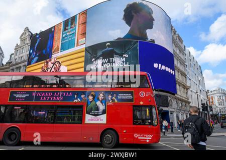 Digitale Werbetafeln im Piccadilly Circus, London, mit rotem Bus, der vorne vorbeifährt. Stockfoto