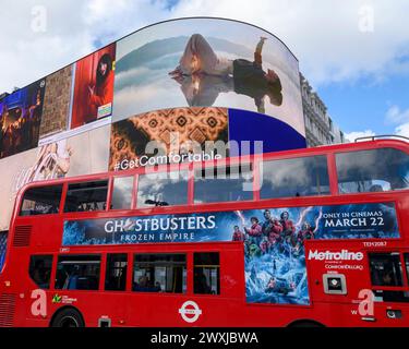 Digitale Werbetafeln im Piccadilly Circus, London, mit rotem Bus, der vorne vorbeifährt. Stockfoto