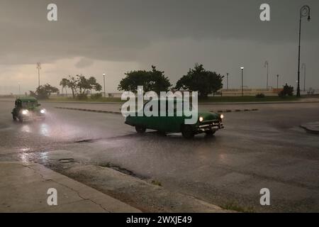 122 Alte grüne Almendron-Autos - Yank Tank, Ford Klassiker aus den Jahren 1949 und 1953 - fahren die Marina Street im harten Regen eines tropischen Sturms hinunter. Havanna-Kuba. Stockfoto