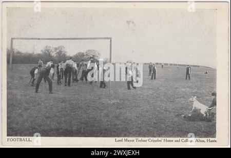 Lord Mayor Treloar Cripples' Home and College, Alton, Hampshire: Football. Postkarte aus dem frühen 20. Jahrhundert, die eine Gruppe von Kindern zeigt, einige mit Krücken Fußball spielen. Ein begeisterter Hund kann man am Pitchside sehen Stockfoto