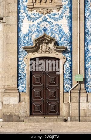 Eine Tür vor der blau-weiß gekachelten Fassade der Kirche Igreja do Carmo in Porto, Portugal Stockfoto