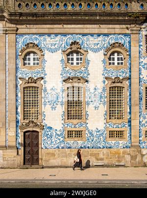 Frau kommt an der Fassade der Kirche Igreja do Carmo vorbei, die mit komplexen blauen und weißen Fliesen geschmückt ist, Porto, Portugal Stockfoto