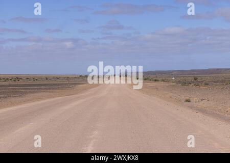 Panoramablick über eine Schotterstraße durch die Wüste wie Steppe im Süden Namibias unter blauem Himmel im Sommer Stockfoto