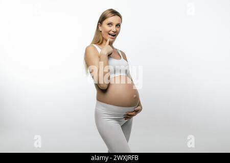 Eine hübsche schwangere blonde Frau, die glücklich und fröhlich ist Stockfoto