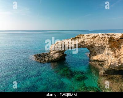 Love Bridge in der Nähe von Ayia Napa auf Zypern. Panoramablick auf die felsige Sommerlandschaft im Cavo Greco Nationalpark, romantische türkisfarbene Meereswellen und einen natürlichen Bogen von Felsen im Wasser Stockfoto