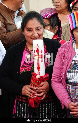 Chichicastenango, Guatemala. 30. März 2024. Indigene Maya-Frauen, die traditionelle Huipiles tragen, halten während einer christlichen und Maya-Zeremonie für Jesus am Heiligen Samstag im Cementerio de Chichicastenango, 30. März 2024, in Chichicastenango, Guatemala, brennende Kerzen. Die katholische Kirche und die Maya-Glaubenssätze haben sich vor langer Zeit in den indigenen Regionen Guatemalas in einem Prozess gemischt, der Synkretismus genannt wird. Quelle: Richard Ellis/Richard Ellis/Alamy Live News Stockfoto