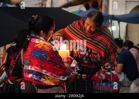 Chichicastenango, Guatemala. 30. März 2024. Indigene Maya-Frauen, die traditionelle Huipiles tragen, zünden bei einer Mahnwache auf den Stufen der Kirche Iglesia de Santo Tomás anlässlich des Heiligen Samstag, dem 30. März 2024 in Chichicastenango, Guatemala, Kerzen an. Die katholische Kirche und die Maya-Glaubenssätze haben sich vor langer Zeit in den indigenen Regionen Guatemalas in einem Prozess gemischt, der Synkretismus genannt wird. Quelle: Richard Ellis/Richard Ellis/Alamy Live News Stockfoto