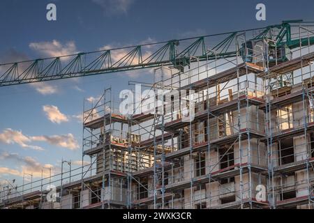 Boom eines grünen Baukrans über der Hülle eines Wohnhauses Stockfoto