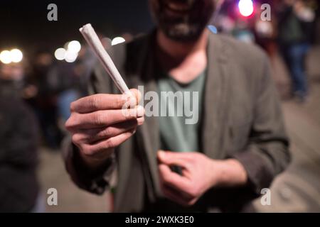 Berlin, Deutschland. April 2024. Ein Mann rollt einen Joint während eines "Rauchens" vor dem Brandenburger Tor. Ab dem 1. April dürfen Erwachsene ab 18 Jahren 25 Gramm Cannabis an öffentlichen Orten besitzen. In privaten Bereichen sind bis zu 50 Gramm hausgemachtem Cannabis zulässig. Drei Pflanzen können privat angebaut werden. Am 1. Juli werden Cannabisclubs für den gemeinsamen Anbau möglich sein. Quelle: Sebastian Gollnow/dpa/Alamy Live News Stockfoto