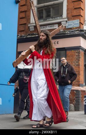 London, Großbritannien. 31. März 2024. Ein Teilnehmer, der als Jesus gekleidet ist, trägt ein Kreuz während des jährlichen Pub Crawl-Events. Eine Gruppe von Pub Crawl-Enthusiasten, verkleidet als Jesus und andere biblische Charaktere, nehmen am jährlichen Christathon Teil, einem Kneipenbummel im Zentrum von London am Ostersonntag. Dies ist der 17. Jahrestag der jährlichen Kneipenbummel mit dem Thema Crucifixion. Quelle: SOPA Images Limited/Alamy Live News Stockfoto