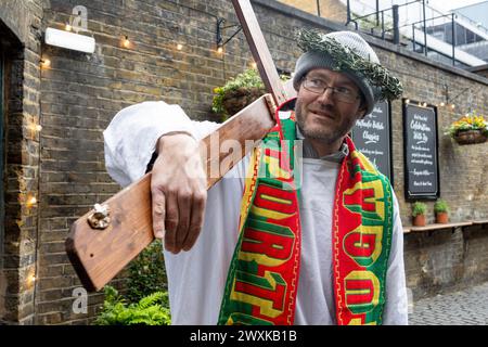 London, Großbritannien. 31. März 2024. Ein Teilnehmer, der als Jesus verkleidet ist, hält das Kreuz während der jährlichen Fancy Dress Pub Crawl Veranstaltung. Eine Gruppe von Pub Crawl-Enthusiasten, verkleidet als Jesus und andere biblische Charaktere, nehmen am jährlichen Christathon Teil, einem Kneipenbummel im Zentrum von London am Ostersonntag. Dies ist der 17. Jahrestag der jährlichen Kneipenbummel mit dem Thema Crucifixion. Quelle: SOPA Images Limited/Alamy Live News Stockfoto