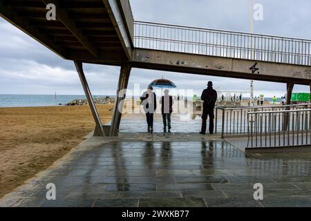 Barcelona, Spanien. 31. März 2024. Ein Paar schützt sich vor dem Regen mit einem Regenschirm während des Sturms Nelson. Blick auf den Strand Barceloneta in Barcelona, Spanien während des Sturms Nelson, der zehn spanische Gemeinden während dieser Karwoche wegen Regen, Wind oder Schnee auf gelber Alarmstufe gehalten hat. Quelle: SOPA Images Limited/Alamy Live News Stockfoto