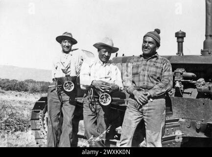 Foto von drei Männern mit Saatsäen sitzen auf einem Traktor in einem unbekannten Indianerreservat in Kalifornien. 1936-1942 Stockfoto