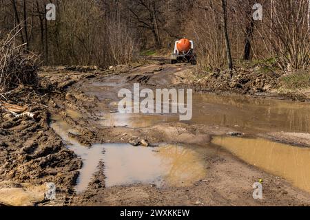 Schlechter Feldweg, große Pfützen im Frühling. Saugwagen fährt auf einer schrecklichen schmutzigen Straße Stockfoto