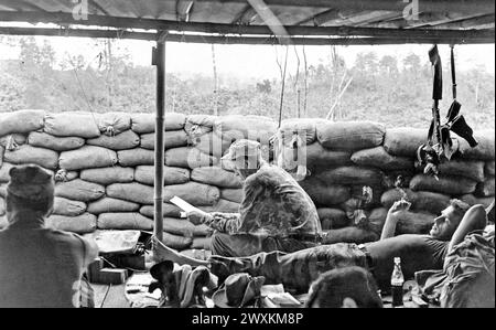 Vietnam war: Ein Berater der Spezialkräfte einer Montagnard-Kampftruppe, erhält die Chance, seine Post in Phey-Shuron zu lesen, einem Lager, das im zentralen Vietnam-Hochland ca. 1964 Stockfoto