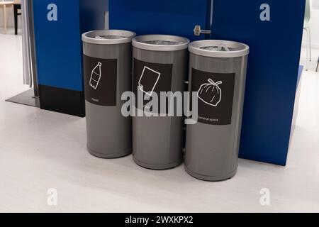 Eine Reihe von drei Recyclingbehältern, die nebeneinander stehen. Die Behälter sind für Kunststoff, Papier und allgemeinen Abfall gekennzeichnet. Stockfoto